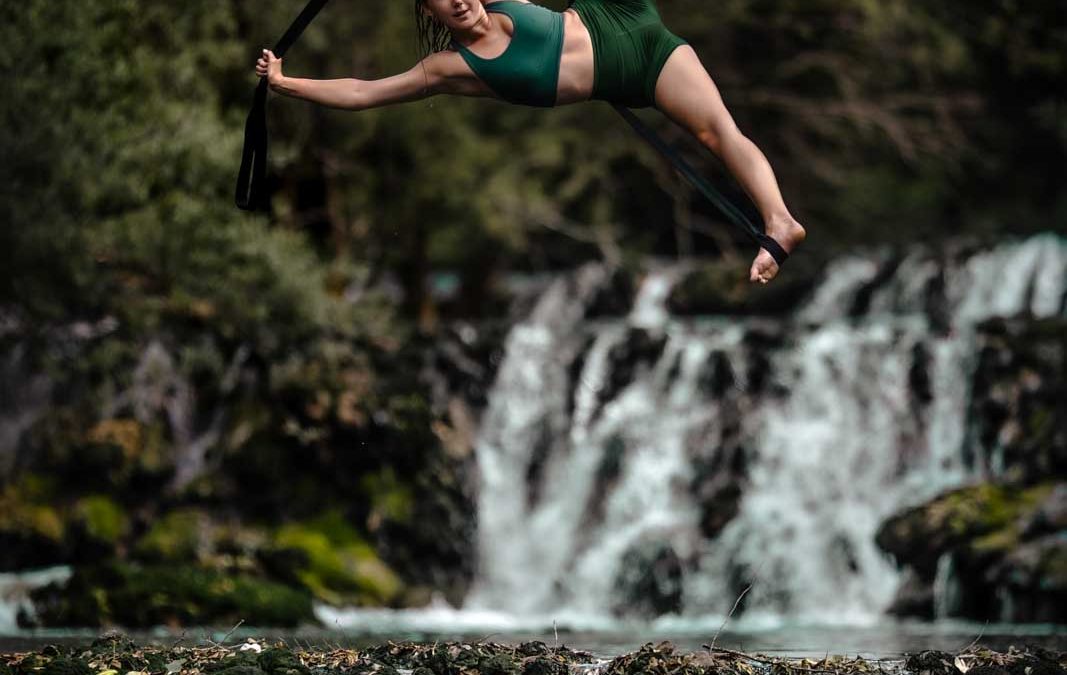 Luftakrobatik vor einem Wasserfall: Artistin an den Strapaten