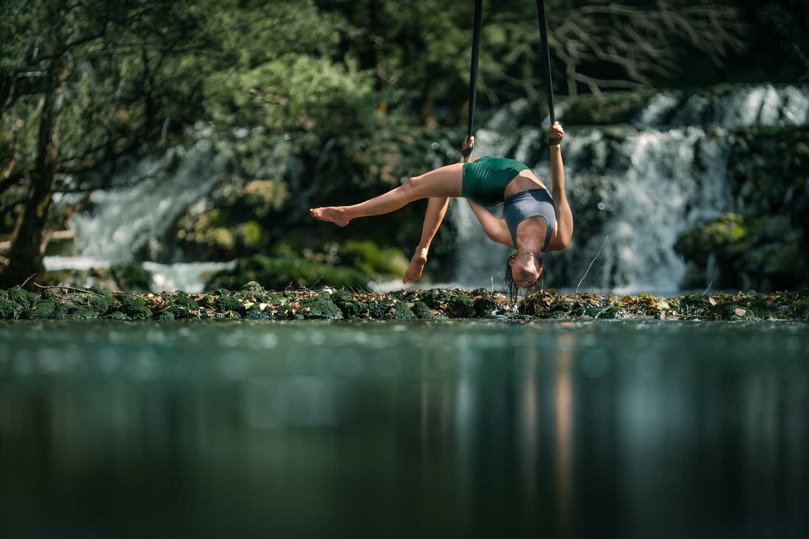 Akrobatin an den Strapaten vor einem Wasserfall.