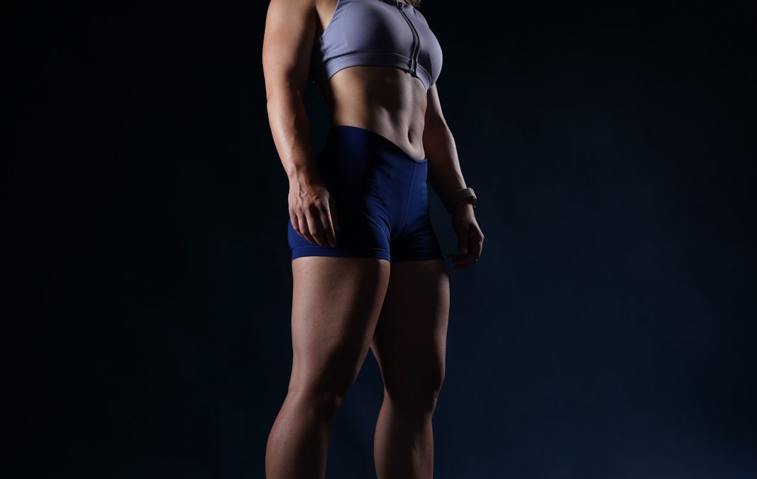 Sportlerin im Fotostudio vor dunklem Hintergrund.