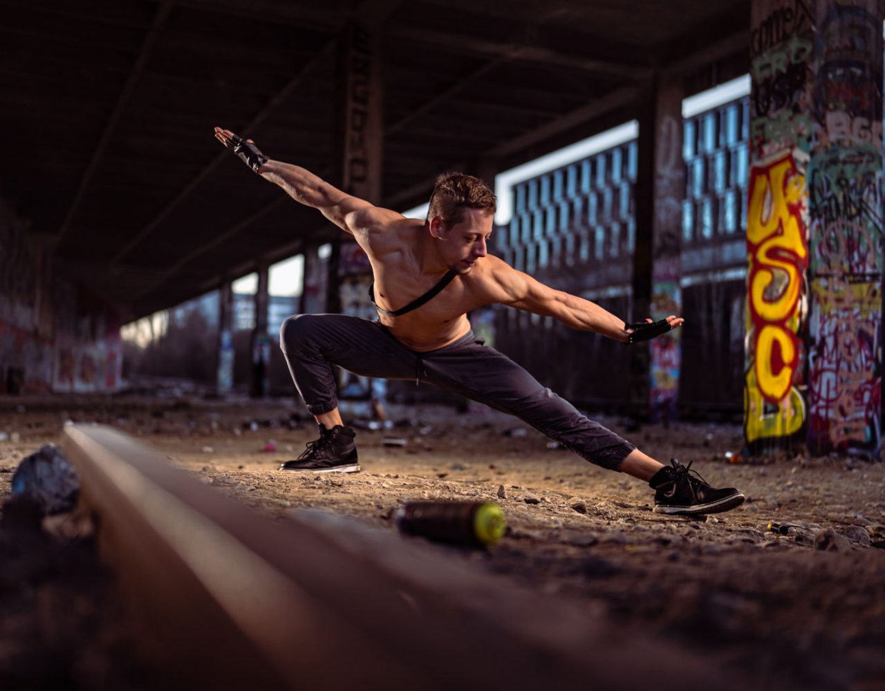 Sportler in dynamischer, tänzerischer Pose an einem verlassenen Bahnhof