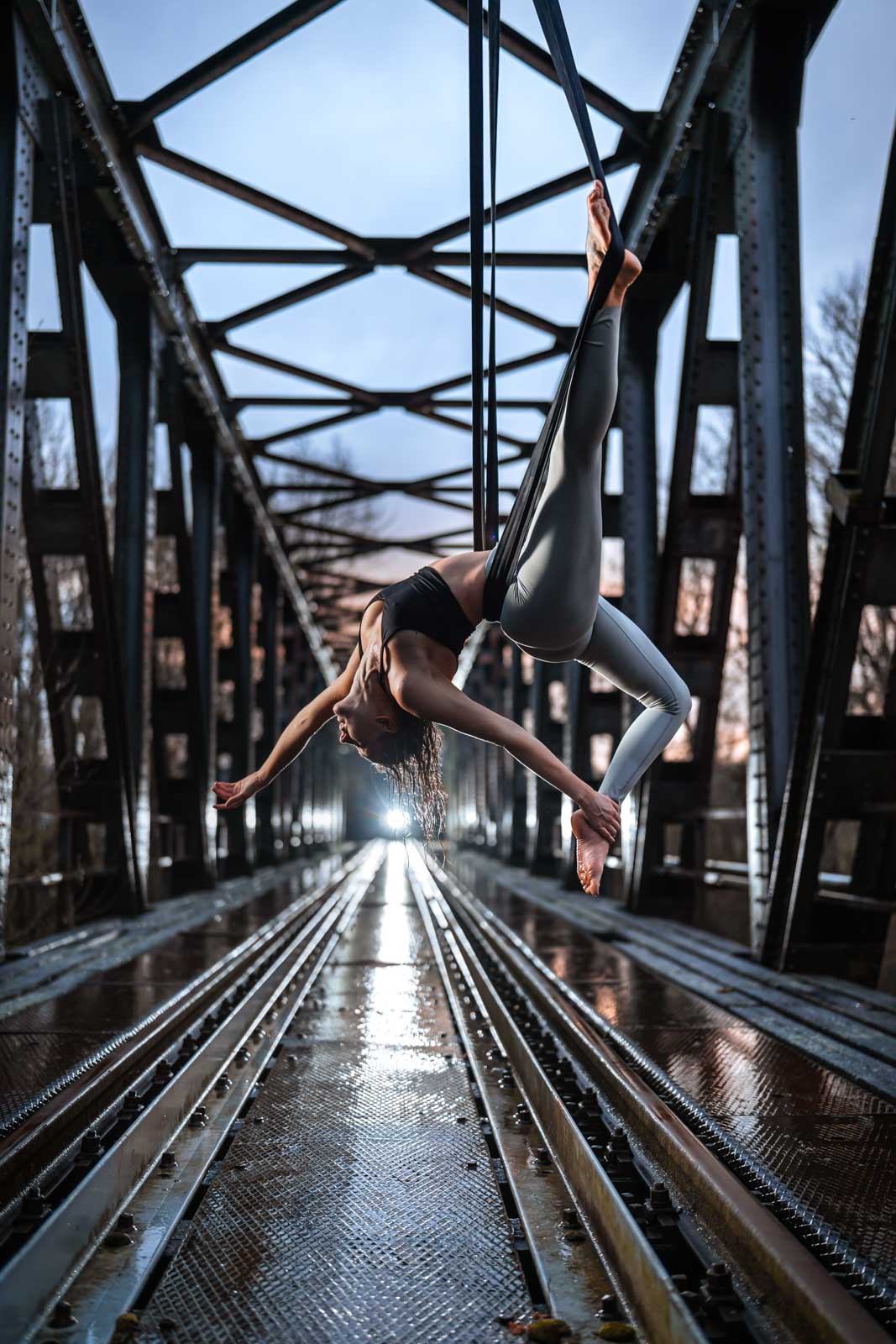 Aerial-Straps Akrobatin an einer verlassenen Eisenbahn-Brücke