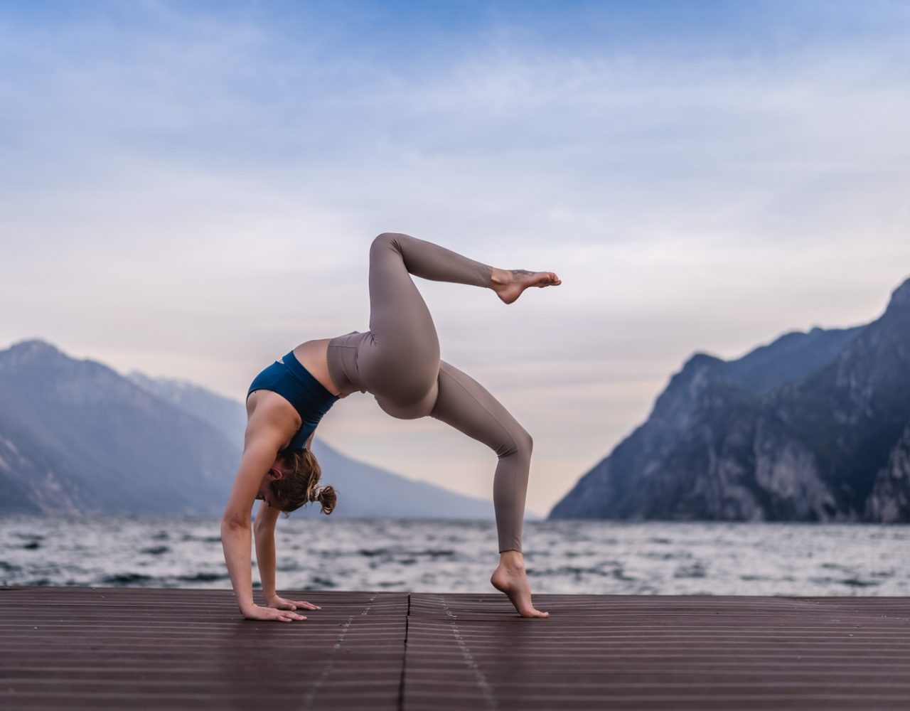 Yoga-Fotografie: Frau macht eine Brücke auf einem Steg am See.