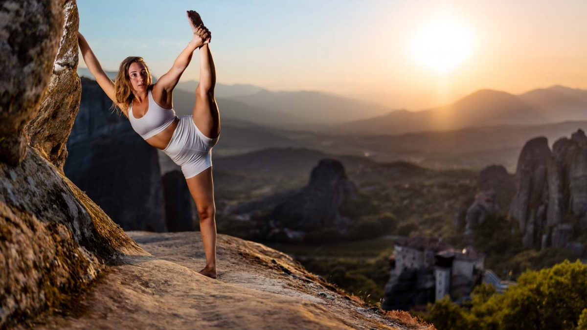 Frau macht Yoga Gymnastik vor atemberaubender Landschaft im Sonnenuntergang.