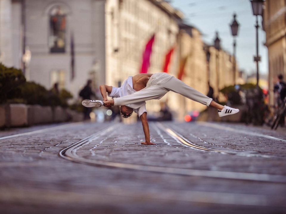 Akrobat steht auf der Straße auf einem Arm.